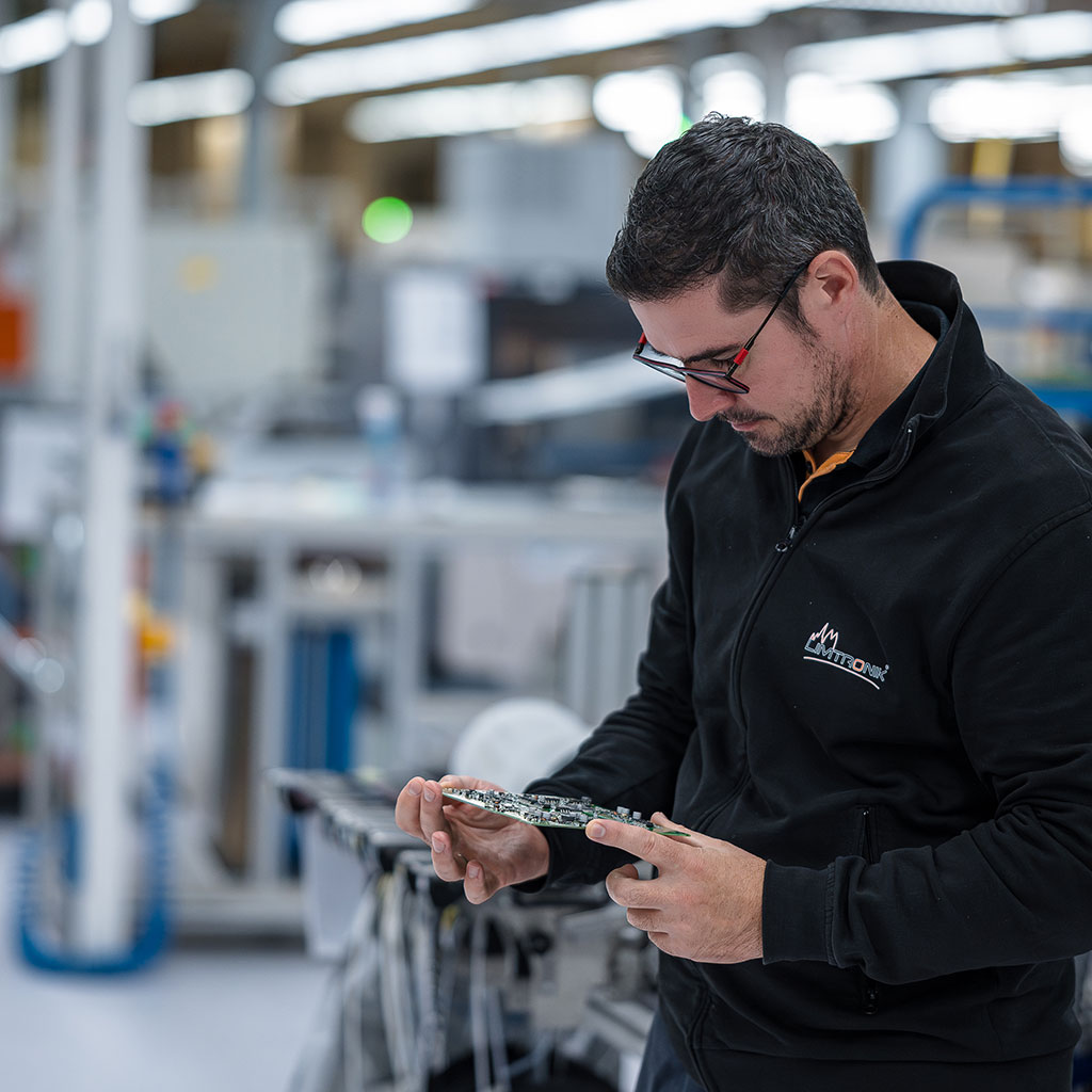 Mitarbeiterin führt Lötarbeiten an einer elektronischen Baugruppe unter genauer Sichtkontrolle durch