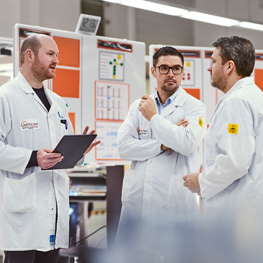 Zwei Fachkräfte in weißer ESD-Kleidung bedienen Testsysteme zur Nachbearbeitung