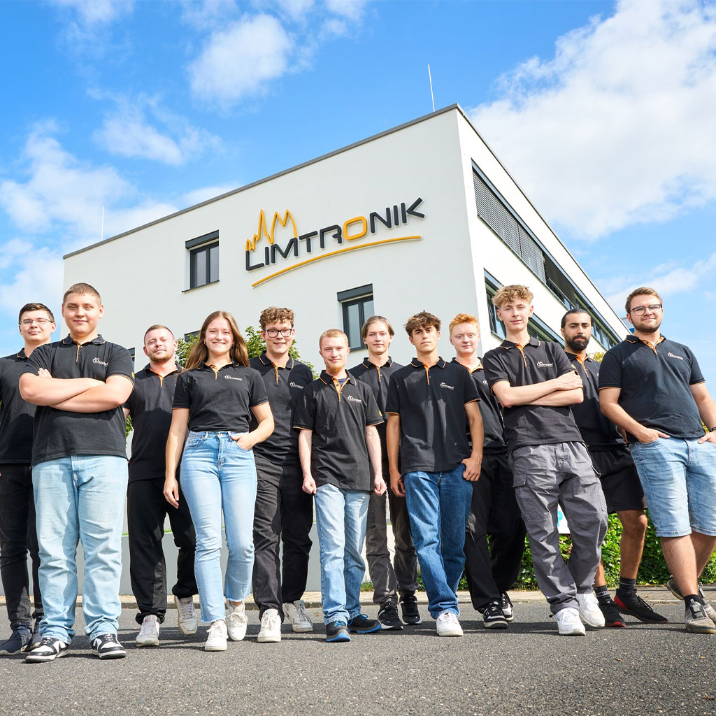 Gruppe junger Auszubildender vor dem Firmengebäude von Limtronik bei sonnigem Wetter