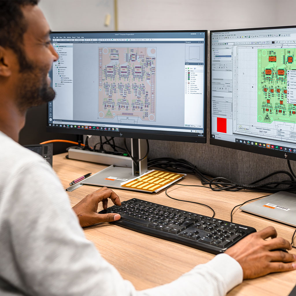 Mitarbeiter arbeitet am Doppeldisplay mit Schaltplansoftware für Leiterplatten-Layouts