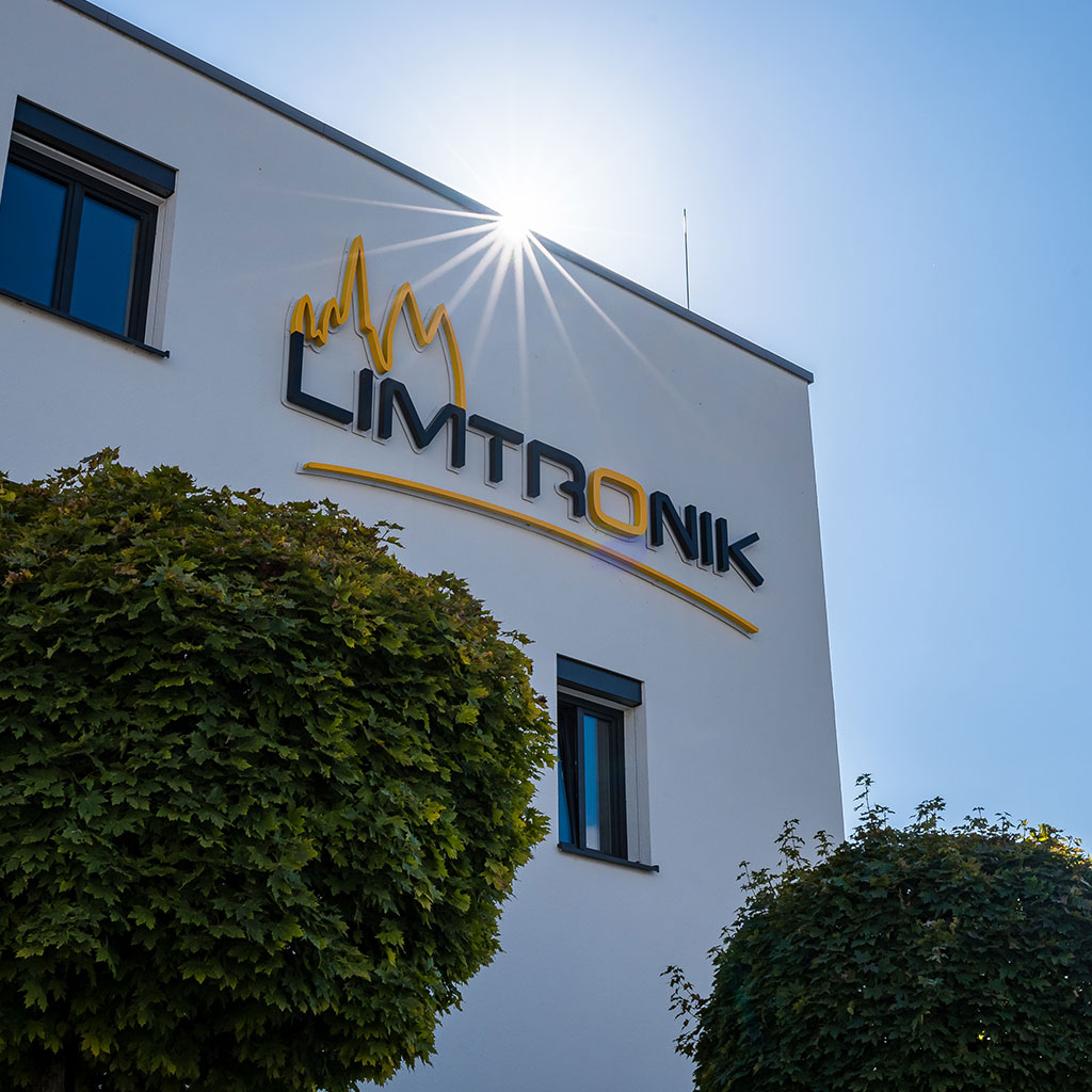 Sonnenlicht scheint über das Firmengebäude von Limtronik mit großem Logo an der Fassade